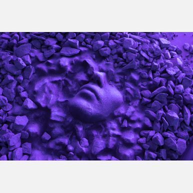 <em>Untitled (Fragment)</em></br> Detail photograph of "Untitled (Fragment)" depicting a partial face seemingly embedded in rocks and lit by purple lighting